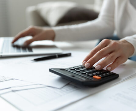 Close,Up,Young,Woman,Using,Calculator,And,Computer,Software,Banking